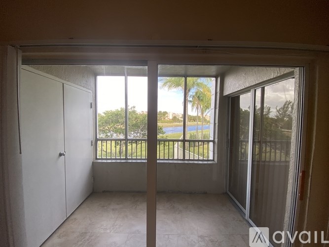 A room with a view of a balcony with a railing and trees.