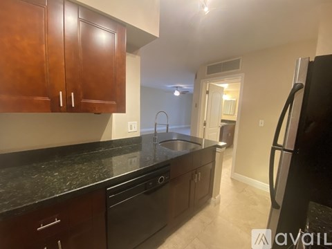 A kitchen with dark brown cabinets and a black countertop.