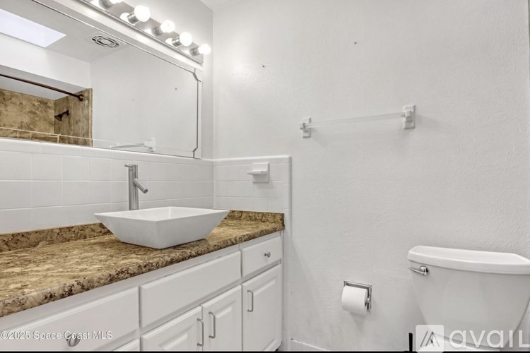 A bathroom with a granite countertop and white fixtures.