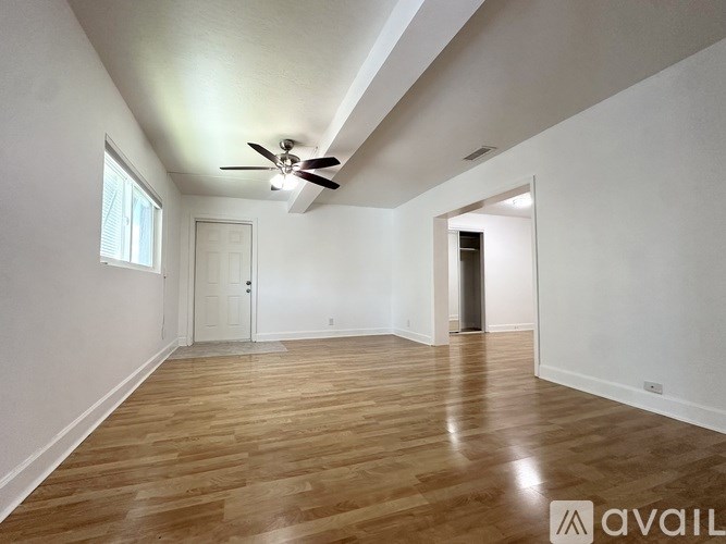 A room with a ceiling fan and wooden flooring.
