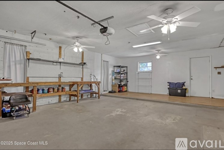 A large empty room with a fan and a table.