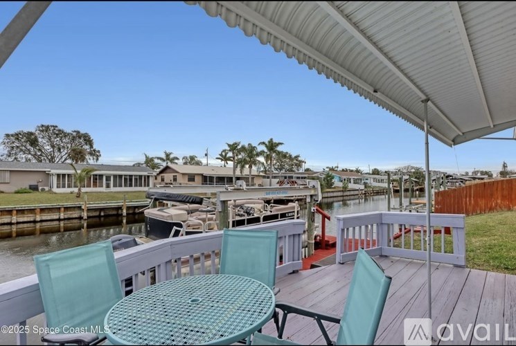 A patio with a table and chairs overlooking a dock.