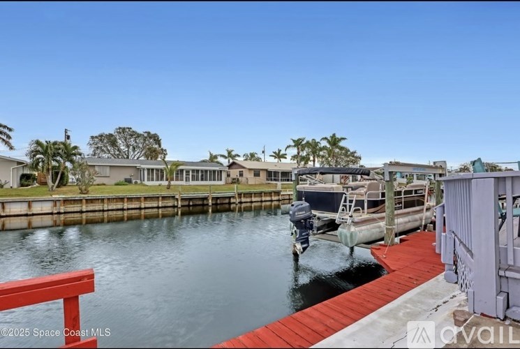 A dock with a red railing and boats in the water.
