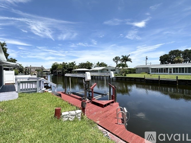 A dock with a red railing extends into a body of water.