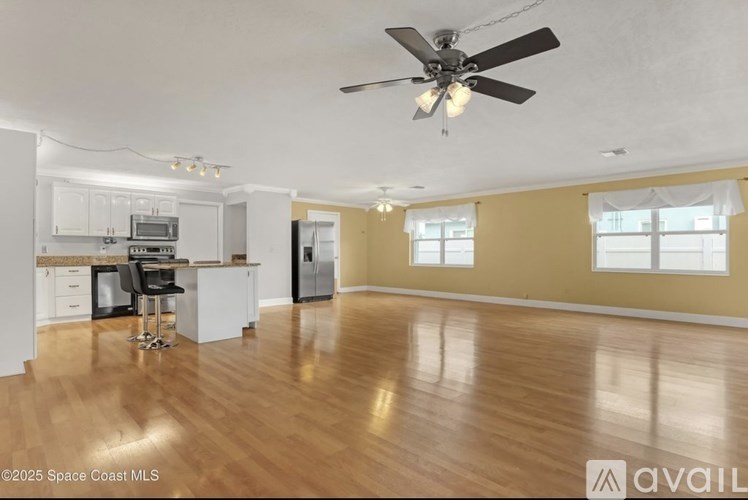 A spacious room with a ceiling fan and hardwood floors.