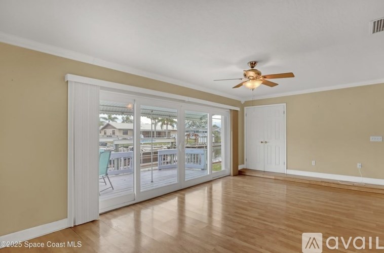 A room with a ceiling fan and sliding glass doors leading to a balcony.