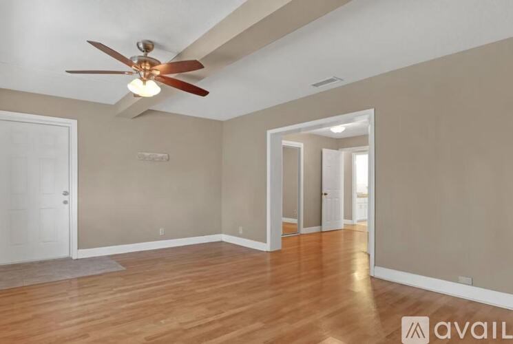 A spacious room with wooden flooring and a ceiling fan.