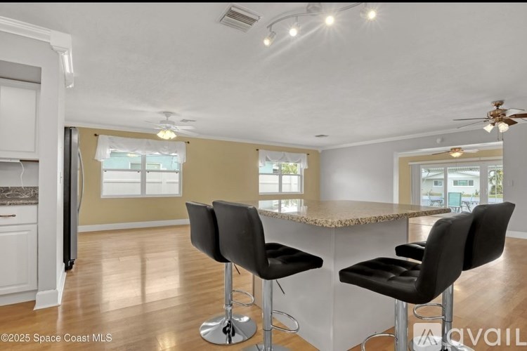 A kitchen with a bar area featuring black chairs and a granite counter.