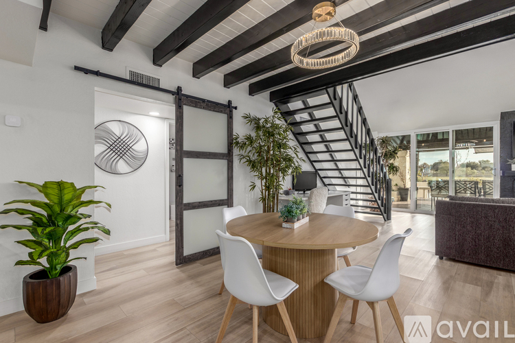 A modern dining room with a wooden table and white chairs.