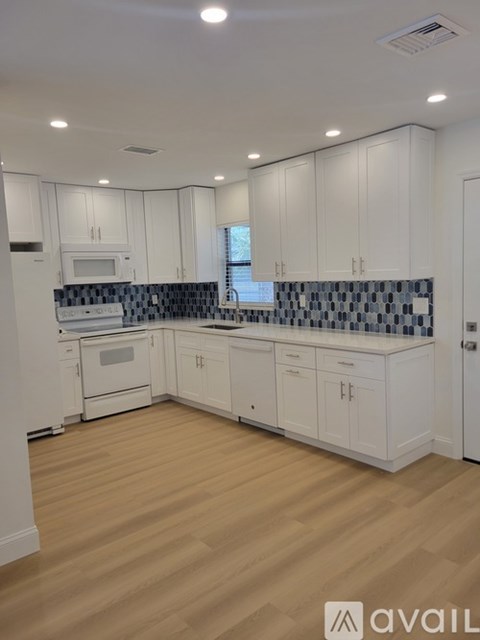 A kitchen with white cabinets and a wooden floor.