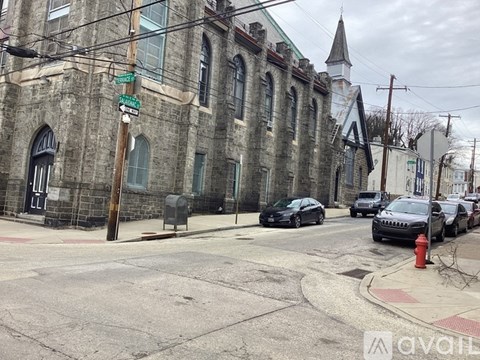 A street view with cars parked on the side and a church building in the background.