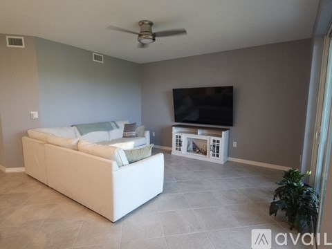A living room with a white couch and a television on a stand.