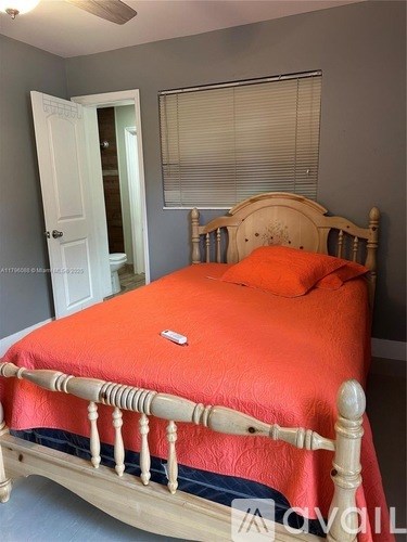 A bed with a wooden frame and an orange bedspread is in the image.