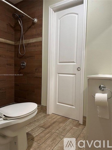 A white door is in a bathroom with a toilet and a shower.