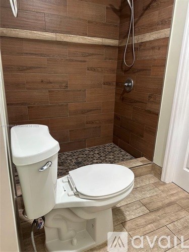 A white toilet with a tank and a shower head in a bathroom.