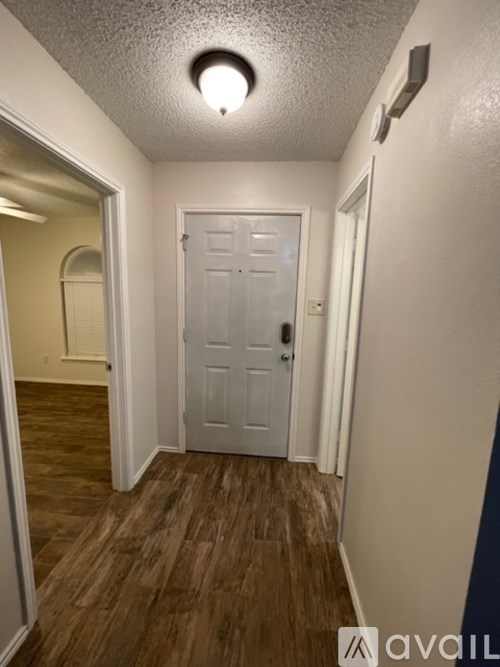 A hallway with a white door and wooden floors.