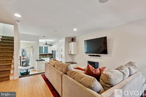 A living room with a couch and a television mounted on the wall.