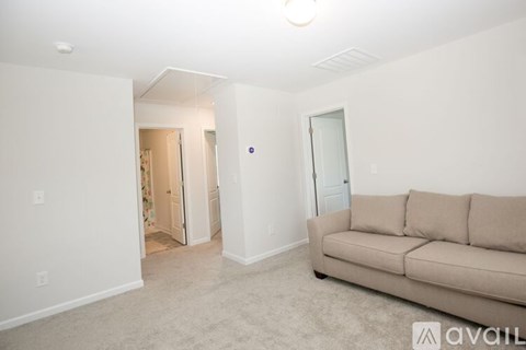 A living room with a couch and a doorway leading to another room.
