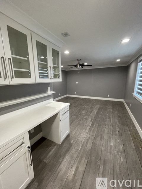 A kitchen with white cabinets and a wooden floor.