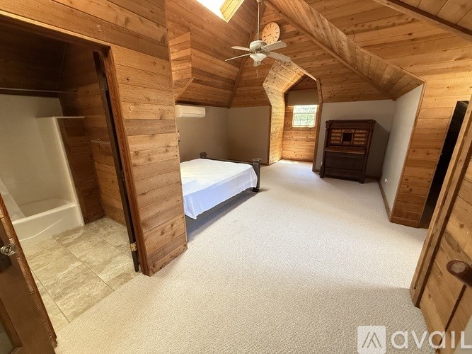 A bedroom with a bed, dresser, and a ceiling fan.
