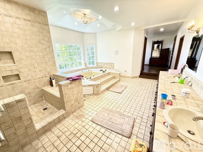 A bathroom with a tiled floor and walls, a shower area, and a sink.