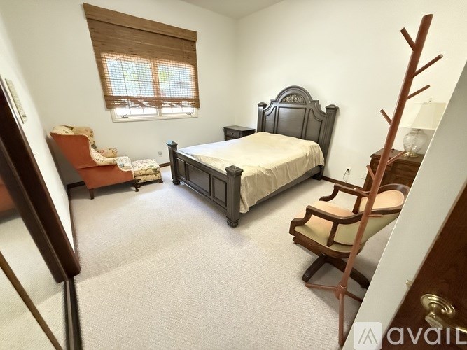 A bedroom with a large bed and a chair.