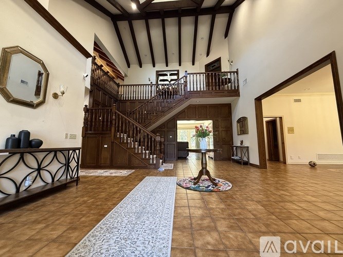 A spacious room with a staircase and a rug in the foreground.