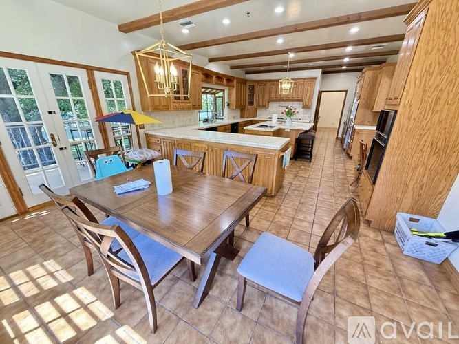 A kitchen with a table and chairs in the foreground and a dining area in the background.