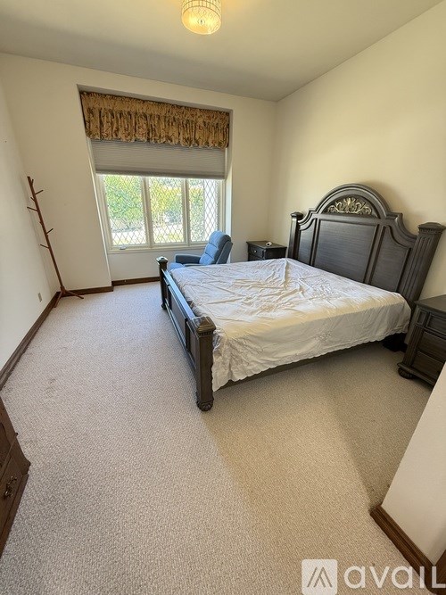 A bedroom with a large bed and a window with curtains.