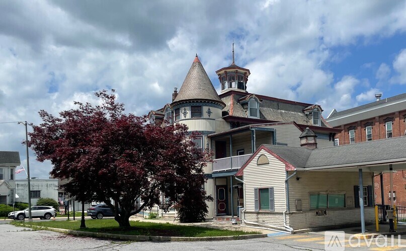A large house with a tower and a tree in front.