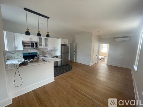 A kitchen with white cabinets and a wooden floor.