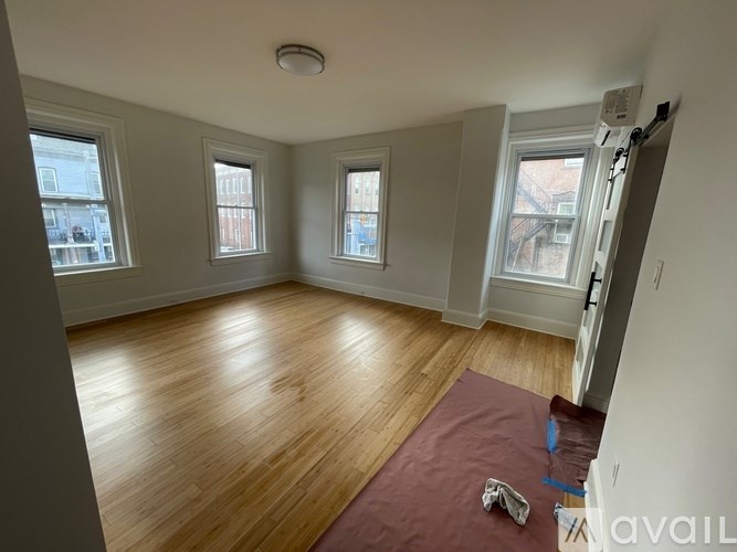 A room with wooden flooring and three windows.
