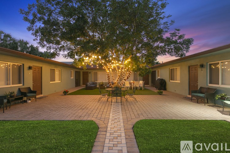 A backyard with a tree and a patio with chairs and a table.