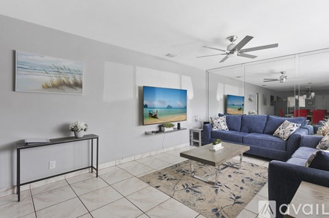 A living room with a blue couch and a painting of a beach scene on the wall.