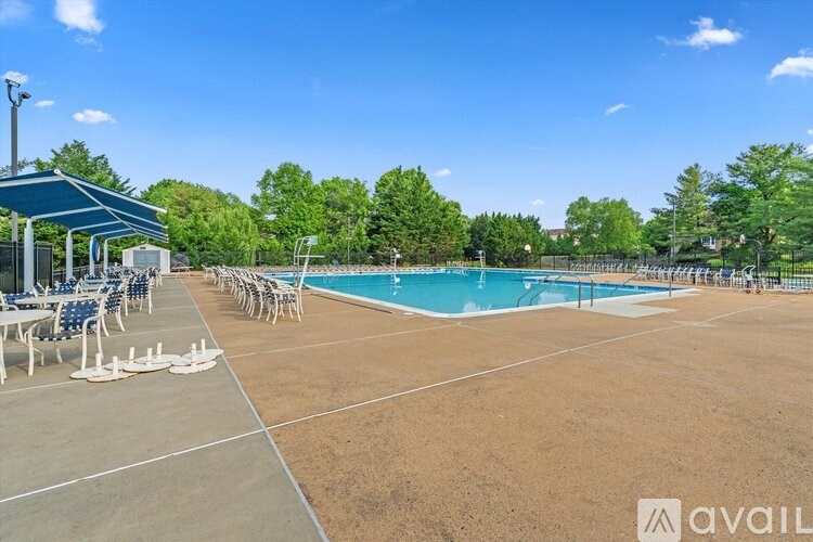 A pool area with a blue sky and trees in the background.