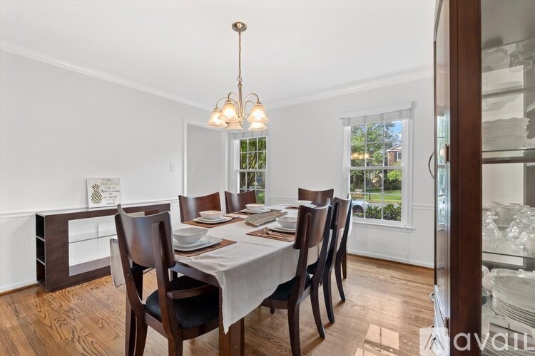 A dining room with a table set for six and a chandelier hanging from the ceiling.
