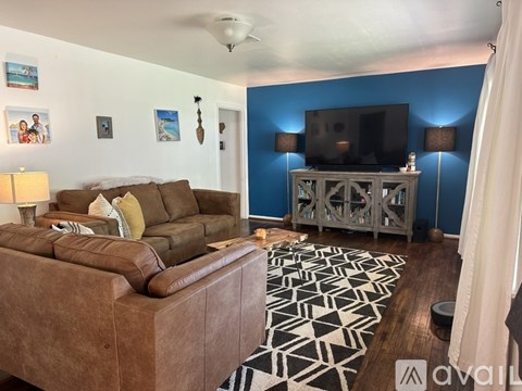 A living room with a brown leather couch and a television on a stand.