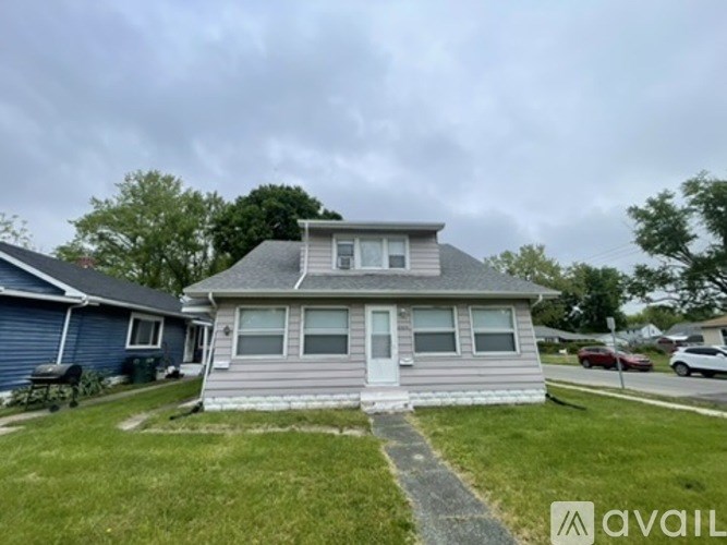 A house with a grey roof and a white door is available for rent.