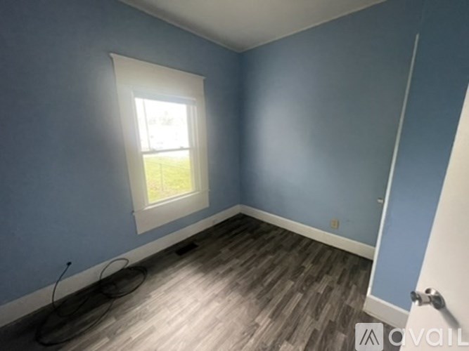 A room with a window and wooden flooring.