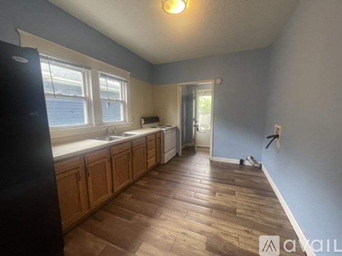 A kitchen with wooden floors and a black refrigerator.