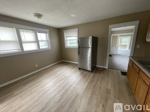 A kitchen with a refrigerator and wooden flooring.