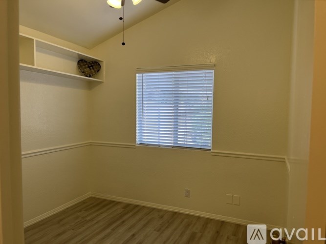 A room with a window covered by white blinds and a wooden floor.