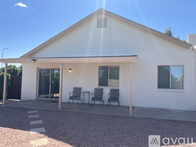 A white house with a gravel driveway and a small patio area.