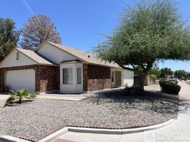 A house with a gravel driveway and a tree in front.