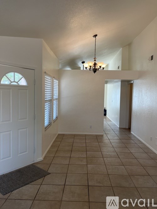 A hallway with a chandelier and a door on the right.