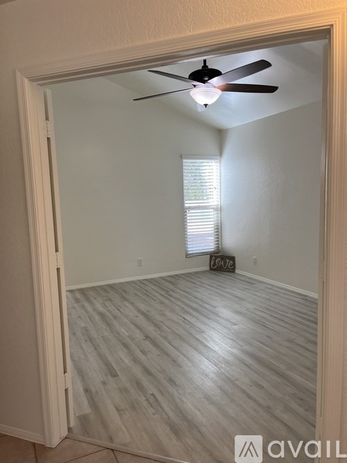 A room with a ceiling fan and wooden flooring.