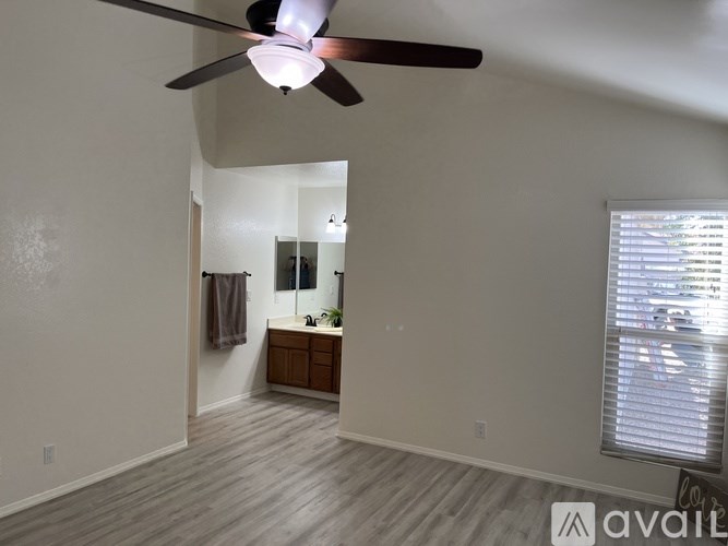 A room with a ceiling fan and a window with blinds.
