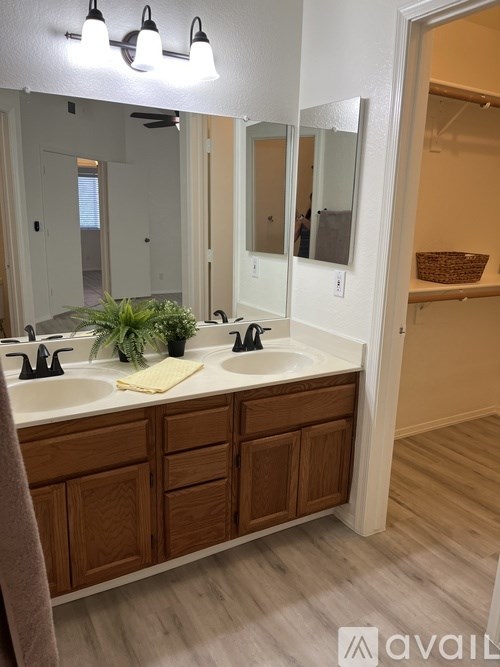 A bathroom with a double sink vanity and a mirror above it.