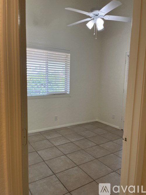 A room with a ceiling fan and tiled floor.