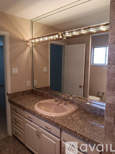 A bathroom with a sink and a mirror with lights under it.